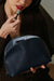 Woman applying lipstick with a blue makeup bag in the foreground
